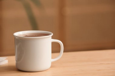 Arka planda, ahşap masada bir fincan sıcak çay. Yakın çekim.