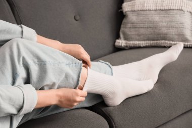 Evde şık beyaz çoraplar giyen genç bir kadın.