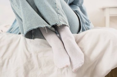 Yatak odasında şık beyaz çoraplı genç kadın bacakları.