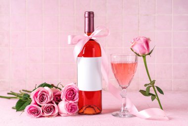 Bir şişe pembe şarap ve güzel güller masasında