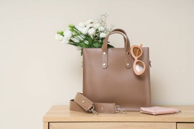 Işık duvarının yanındaki klozette çiçek ve aksesuar bulunan şık bir çanta.