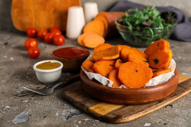 Gri arka planda fırında patates ve soslu kase.