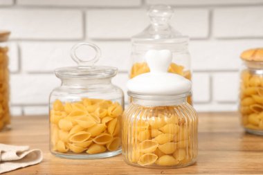 Mutfaktaki masada çiğ makarna kabuğu olan kavanozlar ve kâse.