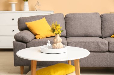 Mimoza çiçekli vazo ve biblo oturma odasındaki masada.