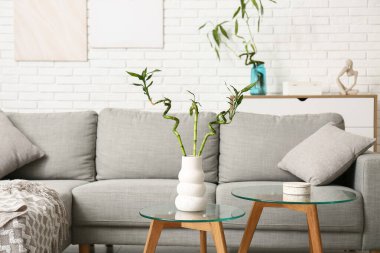 Masada bambu saplı vazo ve tuğla duvarın yanında rahat bir kanepe.