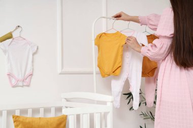 Bebek elbiseleriyle, bebek odasının arka manzaralı genç bir kadın.