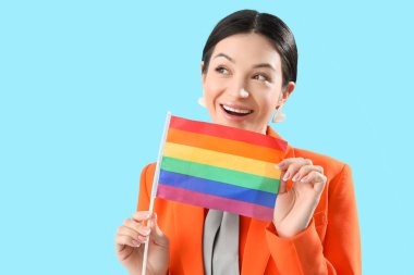 Mavi arka planda gökkuşağı bayrağı olan güzel genç bir kadın. LGBT kavramı
