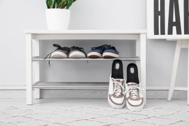 Koridordaki bankın yanında ortopedik tabanlı spor ayakkabılar.