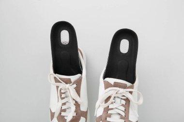 Işık arkaplanda ortopedik tabanlı spor ayakkabılar, yakın plan.