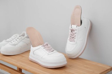 Işık duvarının yanındaki bankta ortopedik tabanlı spor ayakkabılar.