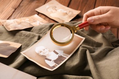 Büyüteçle kadın eli ve akrabalarının eski fotoğrafları. Aile ağacı kavramı