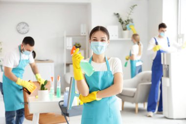 Maskeli ve deterjanlı bayan Asyalı hademe ofisteki temizlik ekibine karşı.