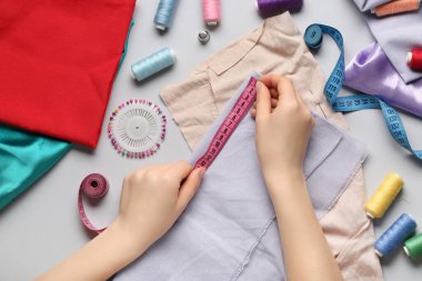 Kadın eli, hafif arka planda dikiş malzemesiyle kumaş ölçer.