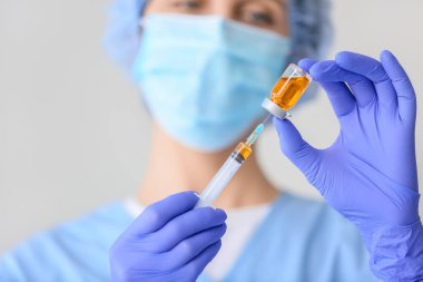 Hastanede ampul ve şırıngayla tıbbi maskeli kadın doktor, yakın plan.