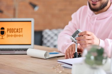 Stüdyodaki masada mikrofon kayıt yapan genç adam, yakın plan.