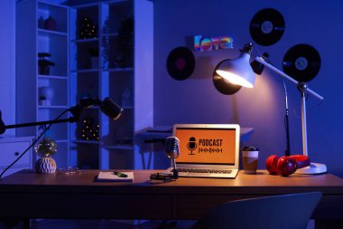 Podcaster 'ın iş yeri. Karanlık stüdyoda dizüstü bilgisayarlar, mikrofonlar ve parlayan lambalar.