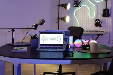 Podcaster 'ın iş yeri. Karanlık stüdyoda dizüstü bilgisayarlar ve mikrofonlar var.