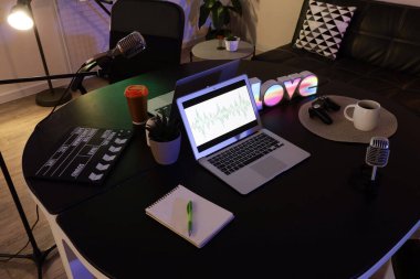 Podcaster 'ın iş yeri. Karanlık stüdyoda dizüstü bilgisayarlar ve mikrofonlar var.