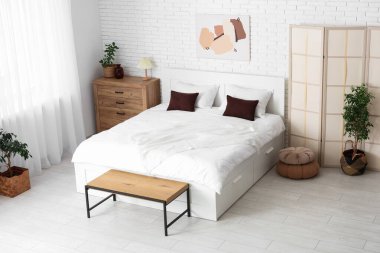 Büyük yataklı, katlanır ekran ve bitkilerle aydınlatma odasının içinde.