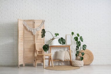 İçinde Monstera bitkileri, masa ve sandalye olan bir oturma odası.