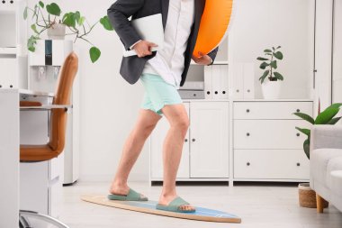 Dizüstü bilgisayarı ve yüzme ringinde sörf yapan genç bir iş adamı. Yaz tatili