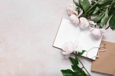 Bej rengi grunge arka planda boş kitap, kolye ve şakayık çiçekleri olan kompozisyon