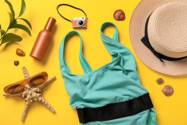 Mayolu kompozisyon, güneş kremi şişesi ve sarı arka planda plaj aksesuarları, yakın plan.