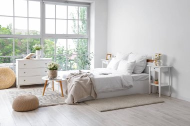 Masalar ve vazolarda papatyalar olan aydınlık yatak odasının içi.