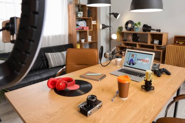 Podcaster 'ın atölyesinin içinde iş yeri, raf üniteleri ve parlayan lambalar var.