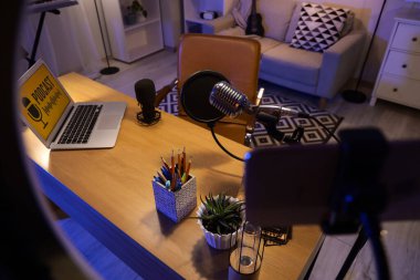 Podcaster 'ın iş yeri. Karanlık stüdyoda dizüstü bilgisayarı ve mikrofonu var.