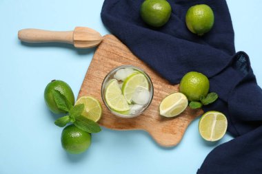 Bir bardak taze mojito kokteyli. Mavi arka planda nane ve limon.