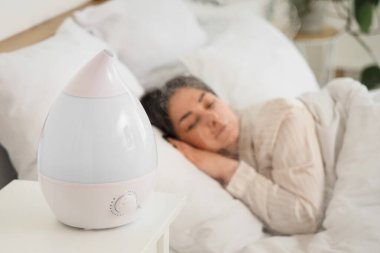Yatak odasında uyuyan kadına karşı hava nemlendirici, yakın plan.