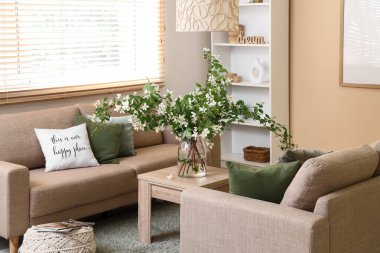 Rahat koltuklar, masa ve vazo, oturma odasında çiçek açan yasemin çiçekleri, yakın plan.