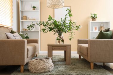 Konforlu kanepeler, masa ve vazo. Oturma odasının içinde çiçek açan yasemin çiçekleri.