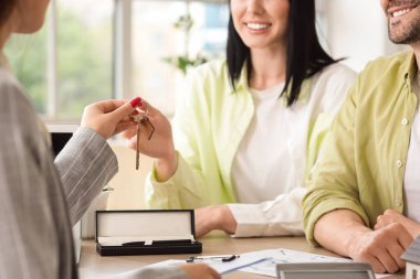 Bayan emlakçı ofiste ev ev dolaşarak anahtarı veriyor, yakın plan.