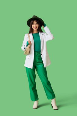 Beyaz ceketli ve yeşil çantalı şık bir bayan.