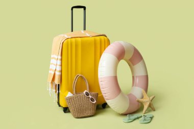 Şişme yüzük, bavul ve yeşil arka planda plaj aksesuarları, yakın plan.