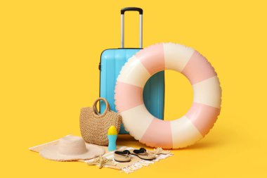Şişirilebilir yüzük, bavul ve turuncu arka planda plaj aksesuarları, yakın plan.