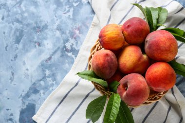 Mavi arka planda bir sepet taze şeftali.