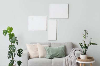 Gri kanepesi, çiçekleri ve resimleri olan modern bir oturma odası.