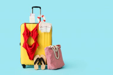 Çanta, mayo ve plaj aksesuarları mavi arka planda, yakın plan.