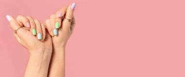 Pembe arka planda güzel manikürlü genç bir kadının elleri.