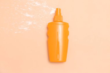 Soluk turuncu arka planda bir şişe güneş kremi.