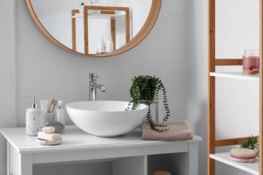 Lavabo, banyo aksesuarları, ayna ve raf ünitesi olan banyonun içi.