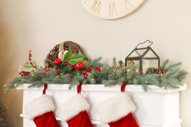 Noel dalları olan şömine rafı ve oturma odasında parlayan ışıklar, yakın plan.