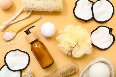 Renkli arka planda farklı banyo malzemeleri ve bir şişe kozmetik ürünü içeren kompozisyon