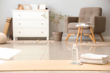 Oturma odasındaki jimnastik paspasının üstünde bir şişe su ve havluyla cep telefonu.