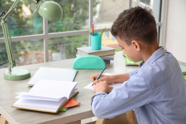 Küçük çocuk evde ders alıyor.