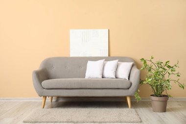 Beyaz yastıklı gri kanepe bej duvarın yanında.