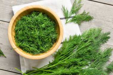 Gri ahşap arka planda taze dereotlu kase